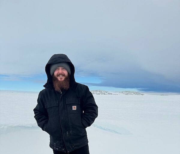 A man in black hoody stands on an icy knoll