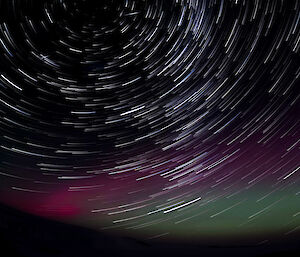 Star trails with a purple and green aurora above Mawson