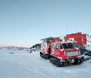 A red hut in the snow with a red hagg in the foreground