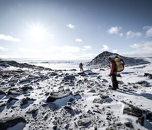 two expeditioners can be seen tracking down the shoreline of a large landscape depicting the Penney Bay