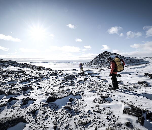 two expeditioners can be seen tracking down the shoreline of a large landscape depicting the Penney Bay