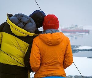 two expeditioners onlooking the beautiful view of the RSV Nuyina supply vessel in the bay out front of casey station
