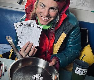 A photo capturing billy's joy while she displays the winning scores after winning some games of Yhatzee at a local hut