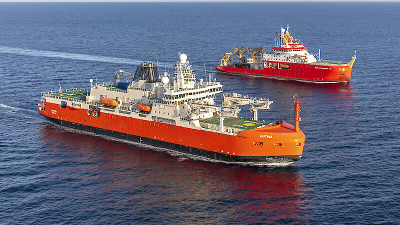 Two large red research ships side by side in the ocean