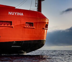 The bow of a large red ship gliding through the sea