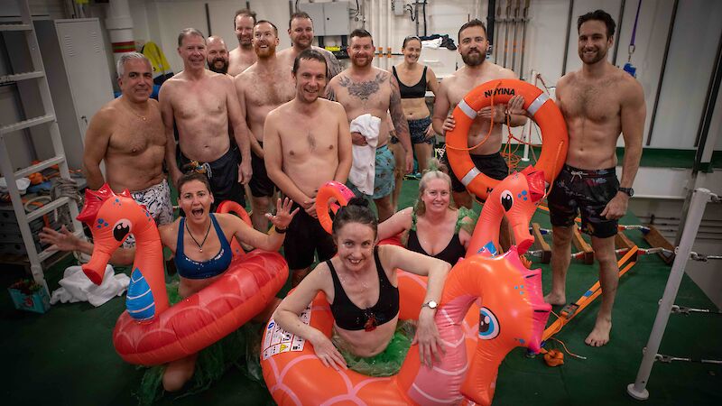 A group of people in bathers, some wearing blow-up sea horse life buoys