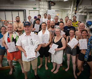 A group of people in bathers holding up certificates and smiling to camera