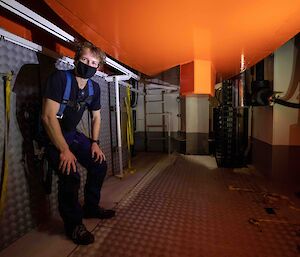 A man standing crouched in a small space under a bright orange keel