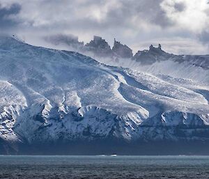 Dramatic, snow dusted cliffs and mountains rise up from the sea.