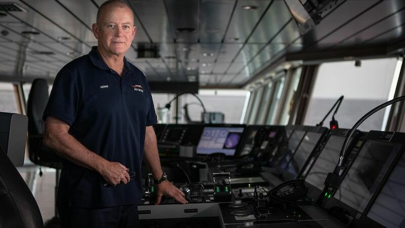A man stands at the bridge of a large ship
