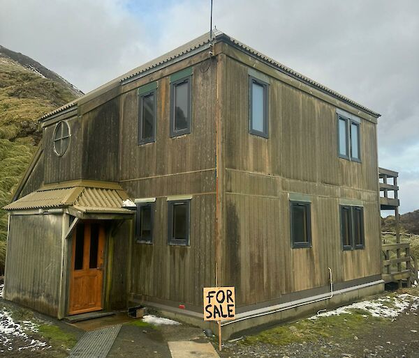 Brown two-storey building with a dirt front yard