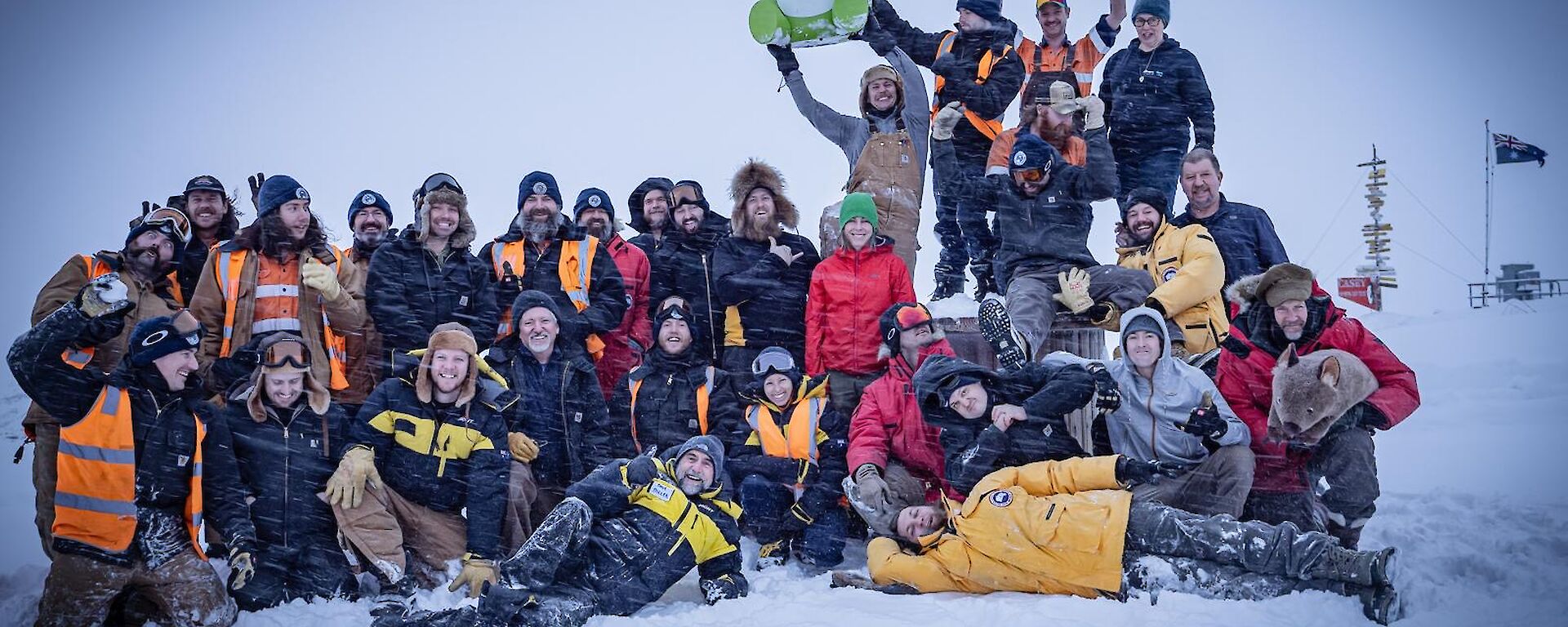 a group photo of the whole station during mid-winter with the Australian flag in the background flying high