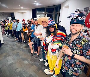 A lineup of the station community during an organized social event sporting costumes with beaming grins