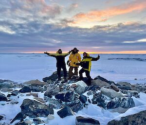 3 expeditioners  delighted of there view spot atop a rocky outcrop over looking a local bay