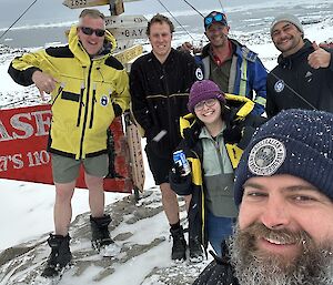 A self captured image of James and fellow expeditioners at the Casey sign as snow flakes grace them