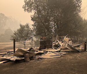 An almost monochromatic type image of a wool shed that has burnt down, with smoke and dust creating a preternatural type effect
