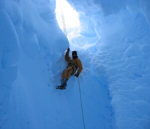 A man climbs down a rope into an icy cavern