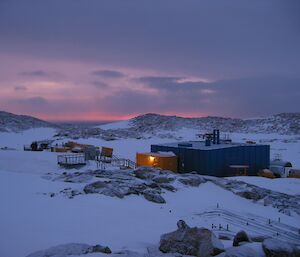 A building with the light on, in a snowy landscape