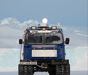 The blue Hagglunds out on the sea ice with the moon rising behind