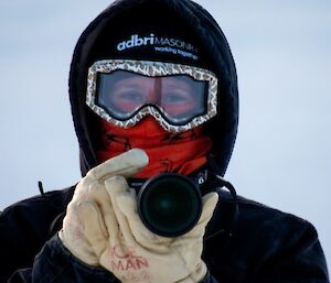 An expeditioner in outside gear to keep warm about to take photographs