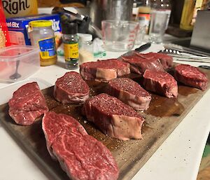 A kitchen bench with tray, steak laid out on the tray ready for cooking