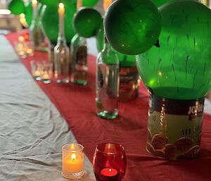 Dinner table decorated with cactus centerpieces made from cans and green balloons