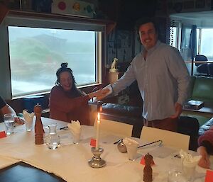 People sitting around the table with white tablecloths and candles