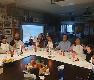 A group of people sitting around an L-shaped white table, laughing