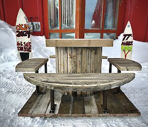 An old electrical cable drum transformed into a practical outdoor round bench with four seats.