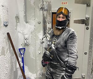 Expeditioner depicted shoveling snow out of the inside of a building at Wilkins Aerodrome.
