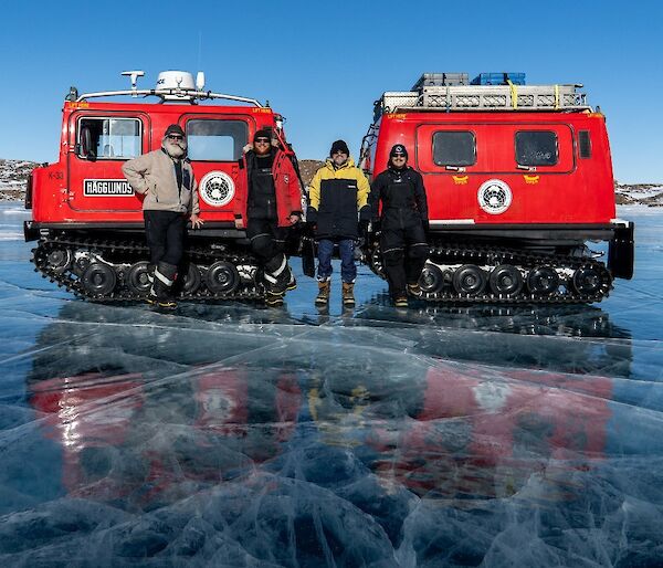 Two red Antarctic tractors stand on a frozen lake