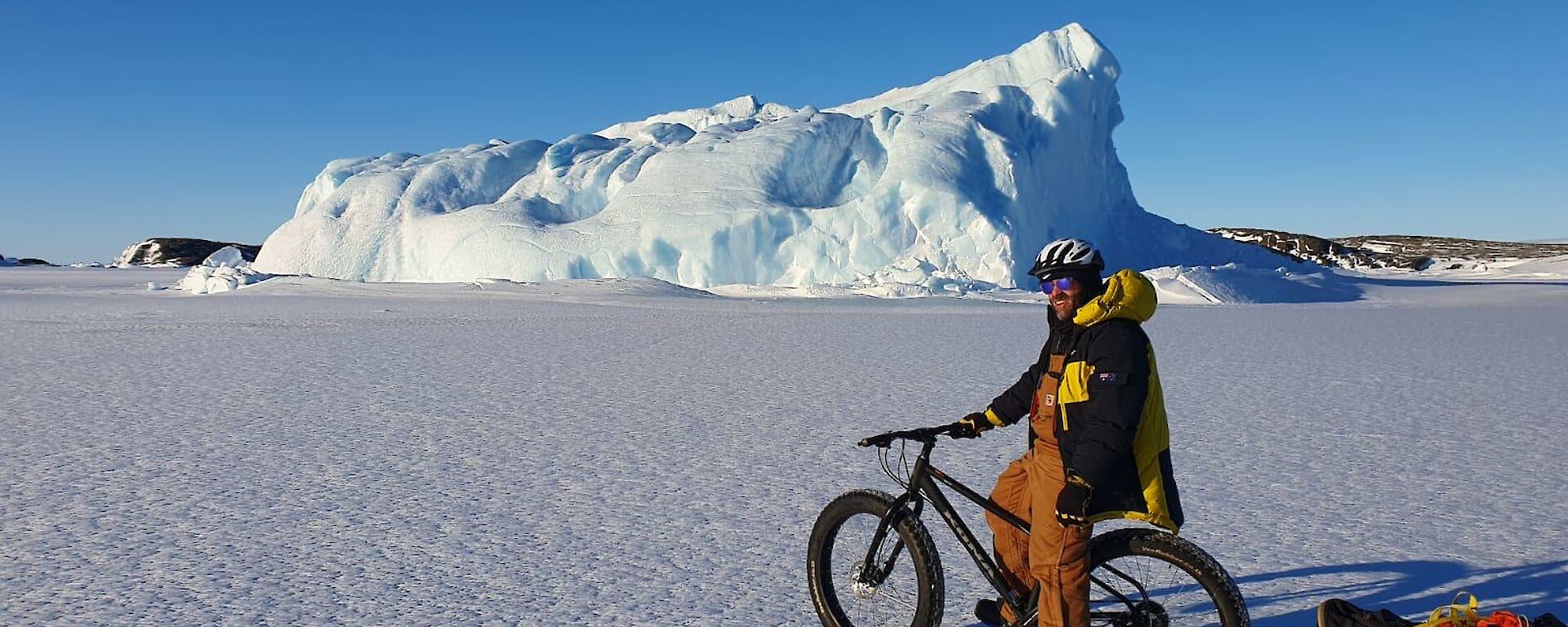David on a bicycle on the sea ice near a medium-sized iceberg