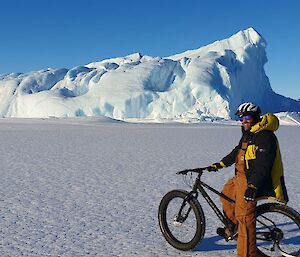 David on a bicycle on the sea ice near a medium-sized iceberg