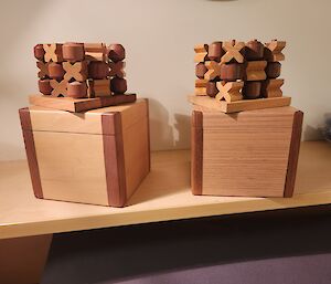 an image of two timber constructed 3D noughts & Crosses with accompanying boxes.