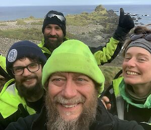 Selfie of four people smiling broadly at camera