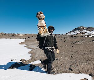 A man carrying a fibreglass guide dog up a rocky hill