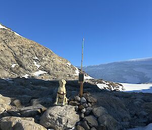 Stay, our guide dog mascot, beside a plaque at the head of a quiet bay where Mawson and his men stepped ashore on 18 February 1931 to claim this part of Antarctica on behalf of King George V, now named Proclamation Point