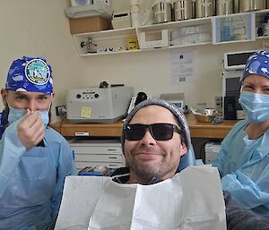 Two station dentists each side of a patient with a bib on.