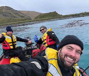 Three people in an inflatable rubber boat just off the shoreline at Macquarie Island.