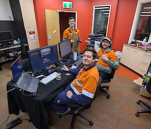 A view with Daniel and Mitch at the desk of the editing suite and camera man Connor in the background