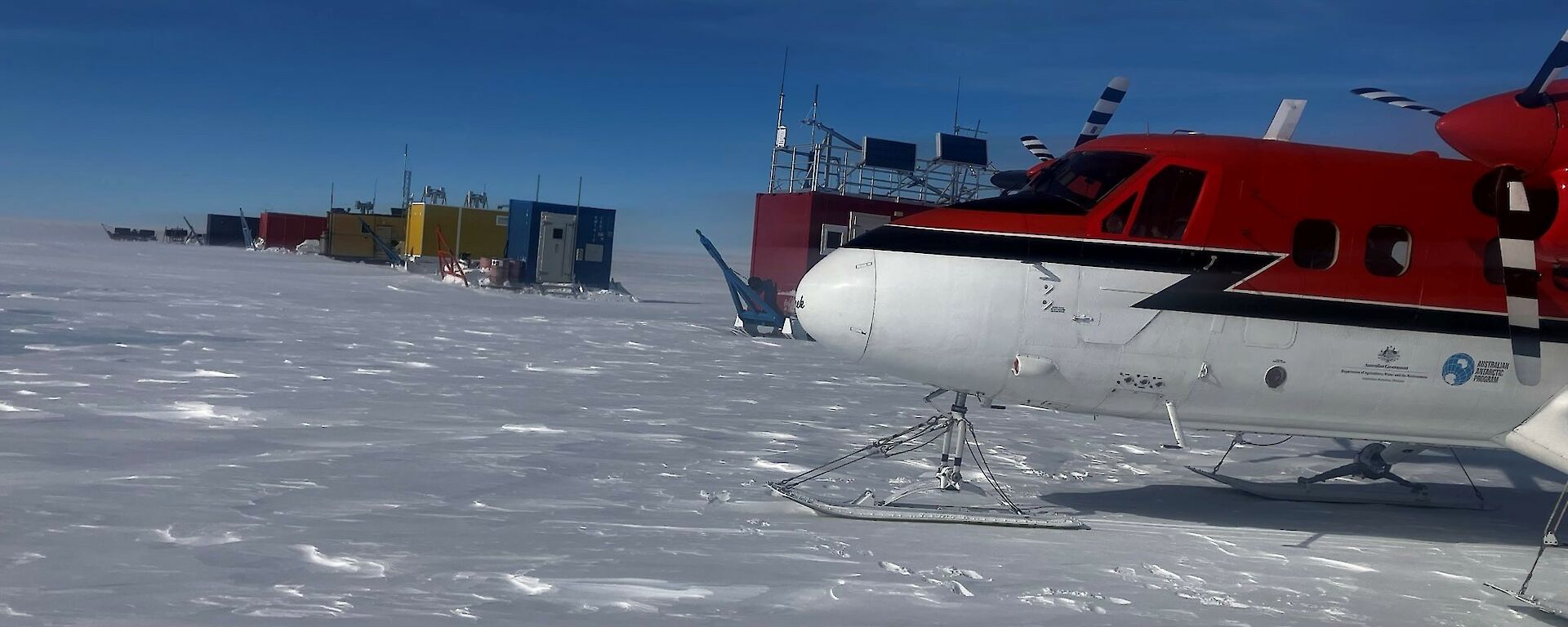 Red and white prop plane on ice under a blue sky