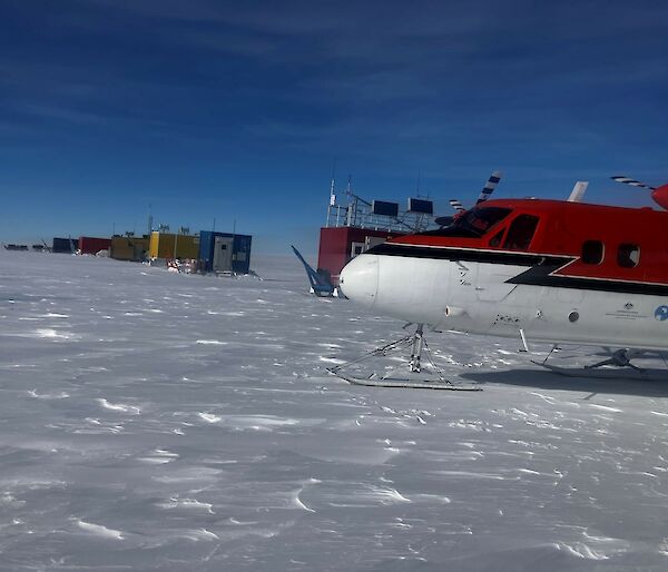 Red and white prop plane on ice under a blue sky