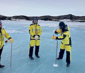 Three people in yellow stand on a frozen lake