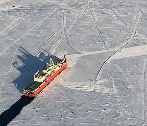 Another aerial of the red icebreaker Nuyina in the ice with a channel of black water behind it