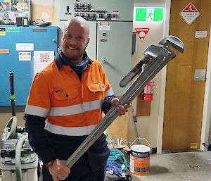 Darryl holding a large steel stilson plumbing tool used when handing over the station from one team to the next