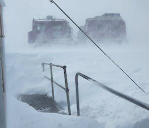 Purple Hagglund vehicle in the middle of the image. Deep snow in the foreground, blowing snow across the image - Blizz conditions. The background is flat grey/white colour, showing lack of vision into the distance.