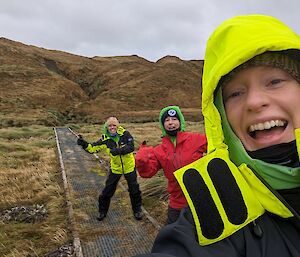 Three women on a walking track with a hill in the background