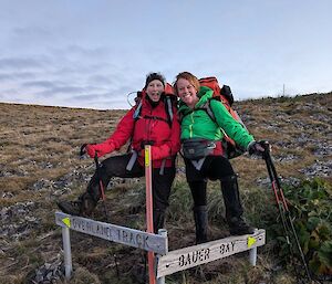 Two women at a crossroads with signs pointing to Bauer Bay on the right and Overland Track on the left