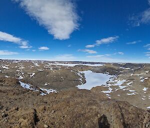 A rocky plain with bits of snow here and there under a blue sky