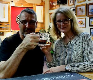 Two expeditioners in the bar at Mawson clinking drinks in celebration
